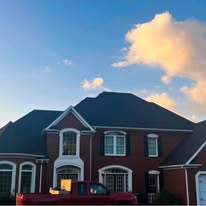 Large two-story brick home with new roof at dusk